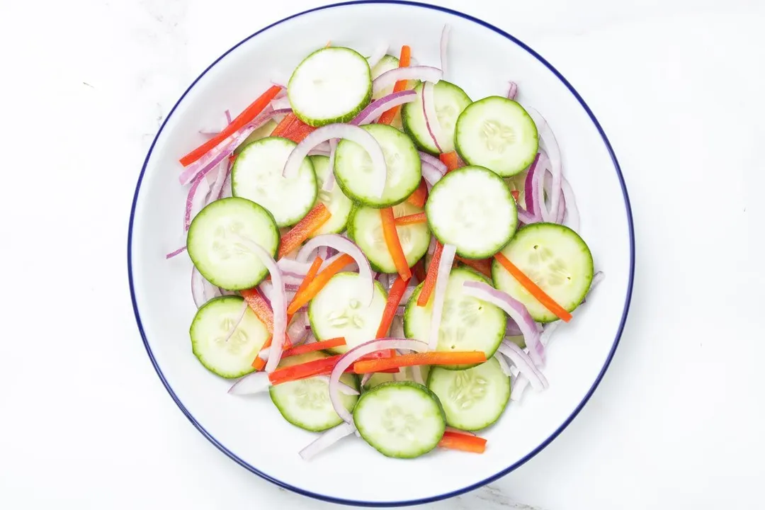 a plate of slices cucumber, onion and bell pepper