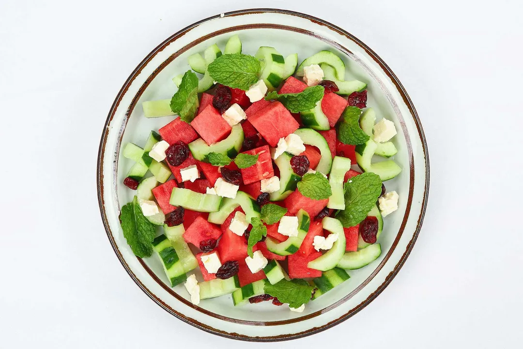 cucumber cubed, watermelon cubed, feta cheese, mint, dried cranberries in a plate