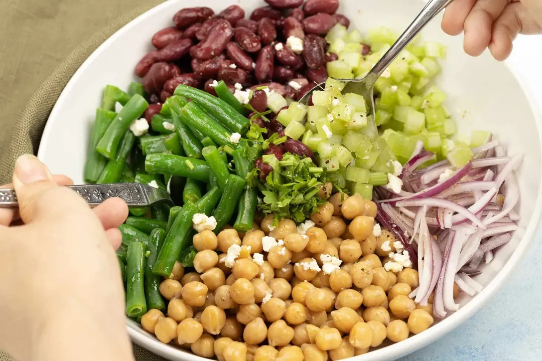 Green beans being mixed with sauce and other ingredients in a plate