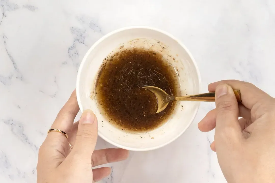 A bowl of a vinaigrette dressing stirred together with a spoon