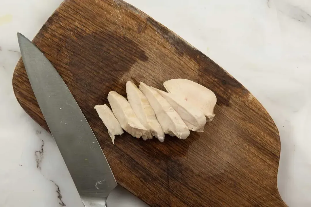 Sliced chicken on a cutting board for Caesar salad