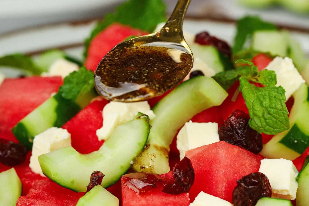 a spoon pouring dressing into salad plate