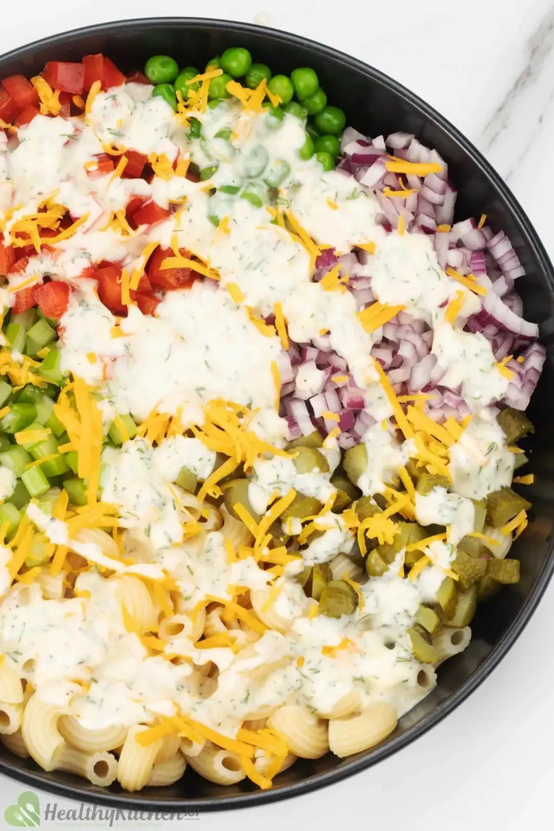 A bowl of macaroni salad with diced vegetables and white dressing in the middle.