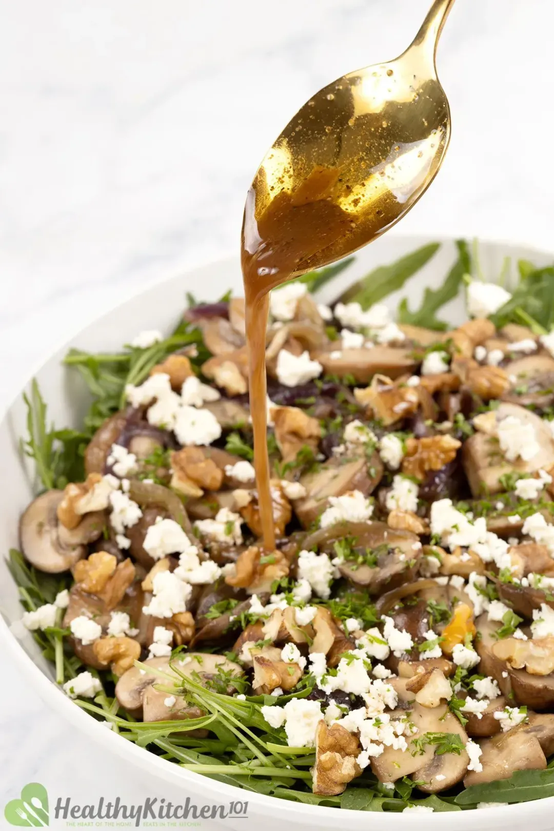 A bowl of mushroom salad with sliced mushrooms, walnuts, cheese, and dressing on top.