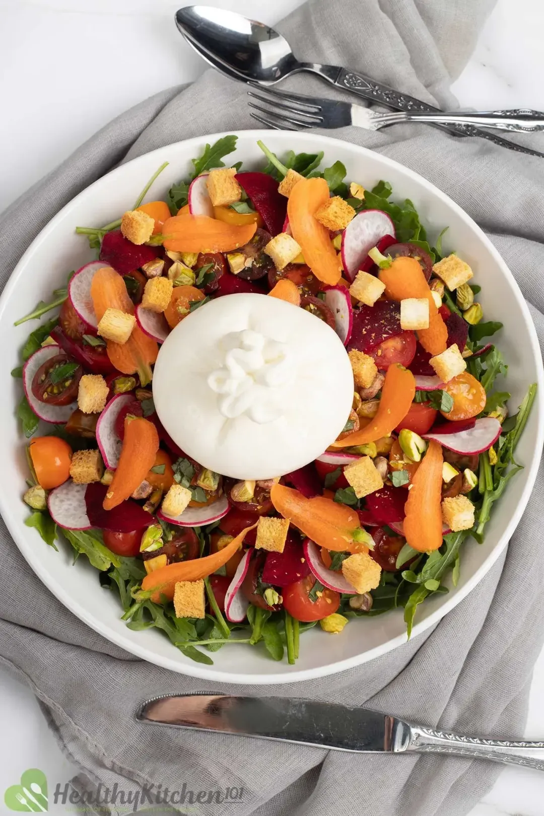 A plate of Burrata salad with arugula, cherry tomatoes, and burrata cheese ball in the middle