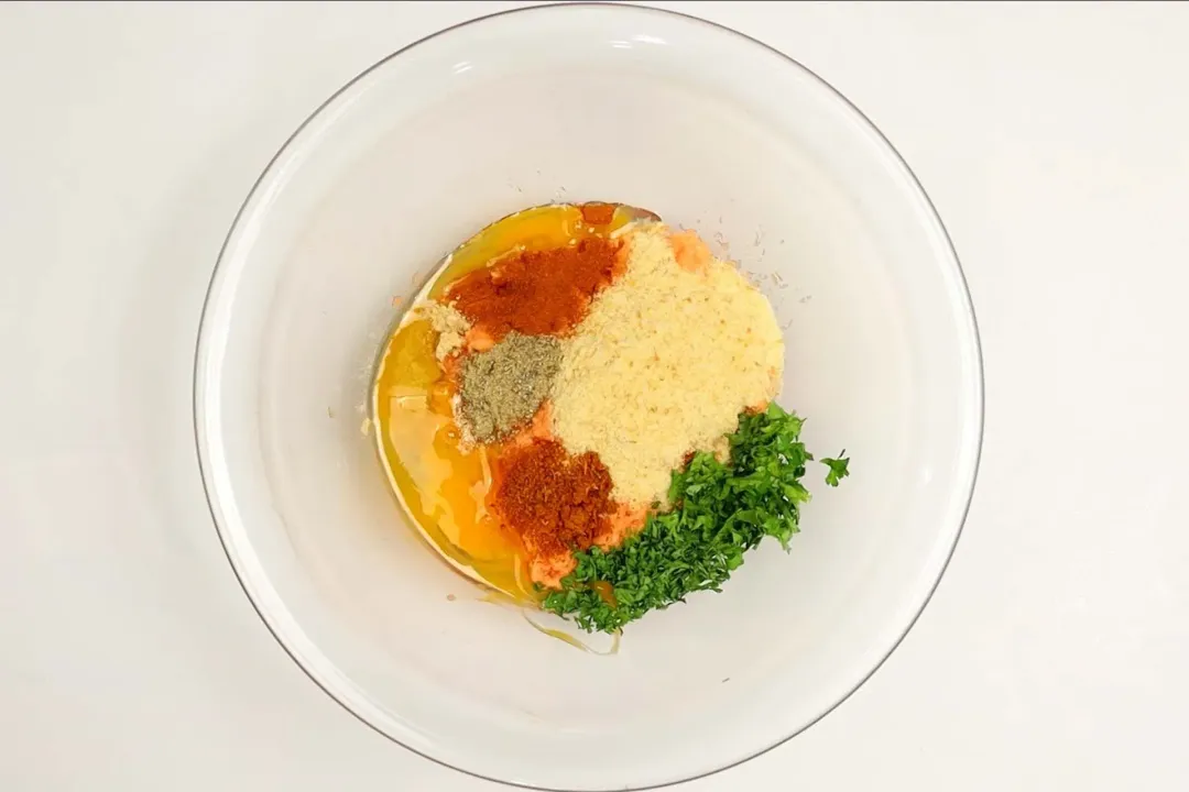 A glass bowl of a mix of herbs, spices, and seasonings.