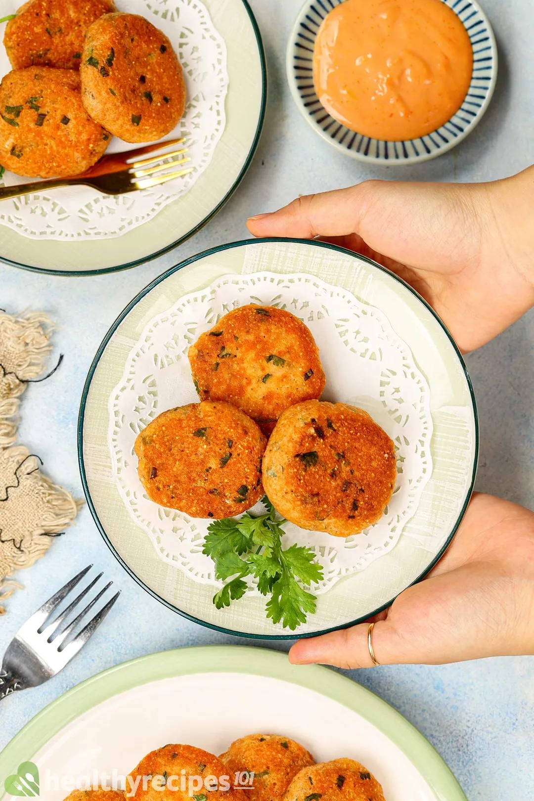 two hand holding a plate of salmon patties