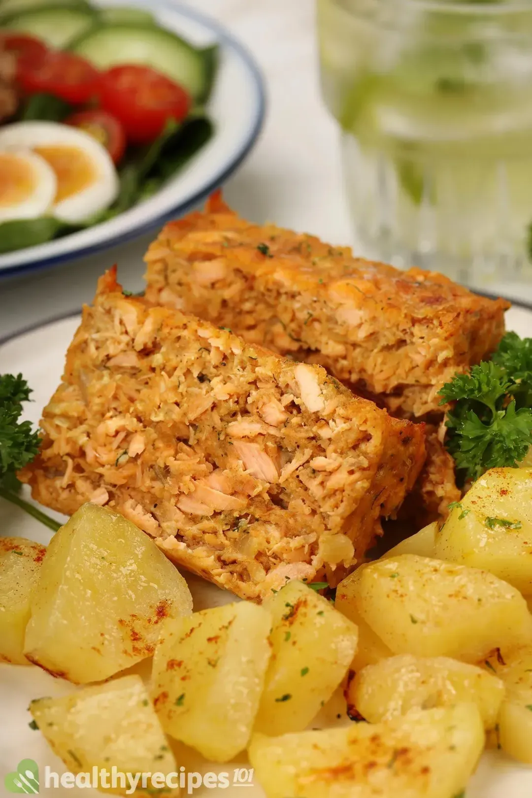 A dish containing two pieces of salmon cakes laid near small potato cubes