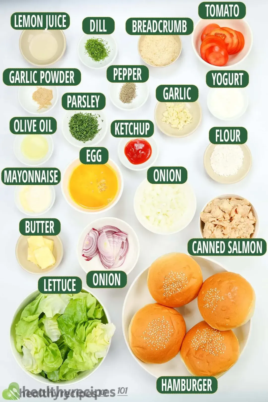 Bowls containing lettuce leaves, hamburger buns, canned salmon, tomato slices, small butter blocks, minced garlic, ketchup, and various condiments