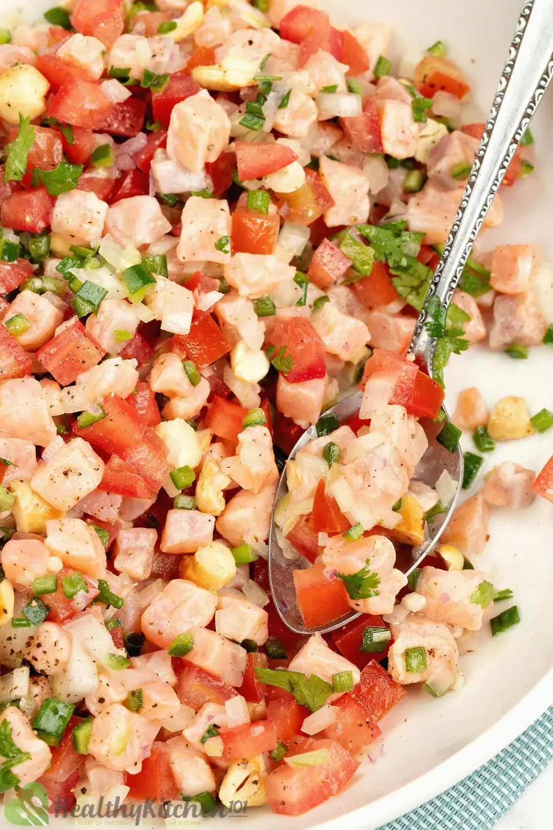 A Lomi Lomi salmon salad served on a white plate and with a silver spoon dunked in