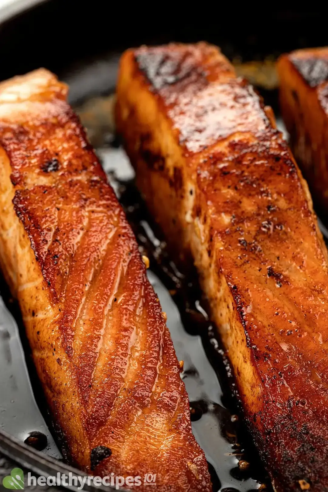 A close-up shot of pan-seared salmons that are brown, glossy, and have charred edges