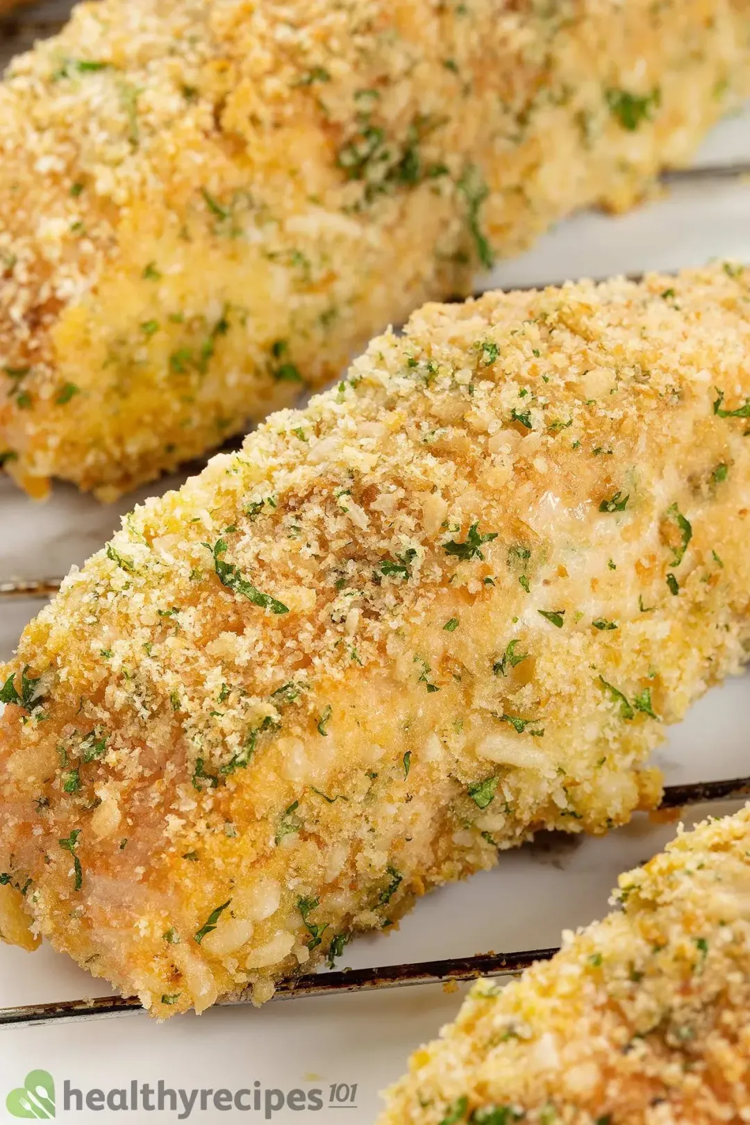 A close-up shot on pieces of salmon fillets crusted in a layer of breadcrumbs, parmesan, and chopped parsley