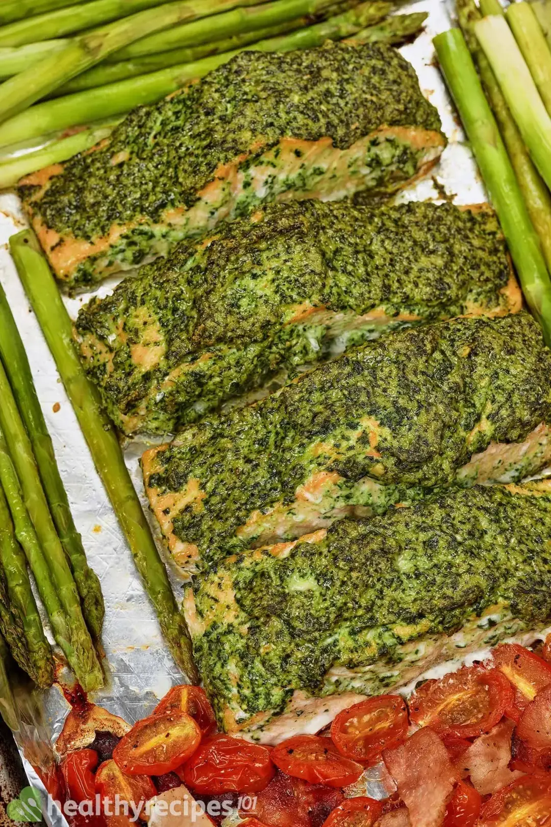 A close-up shot of a baking tray full of pesto salmon and baked vegetables taken from above