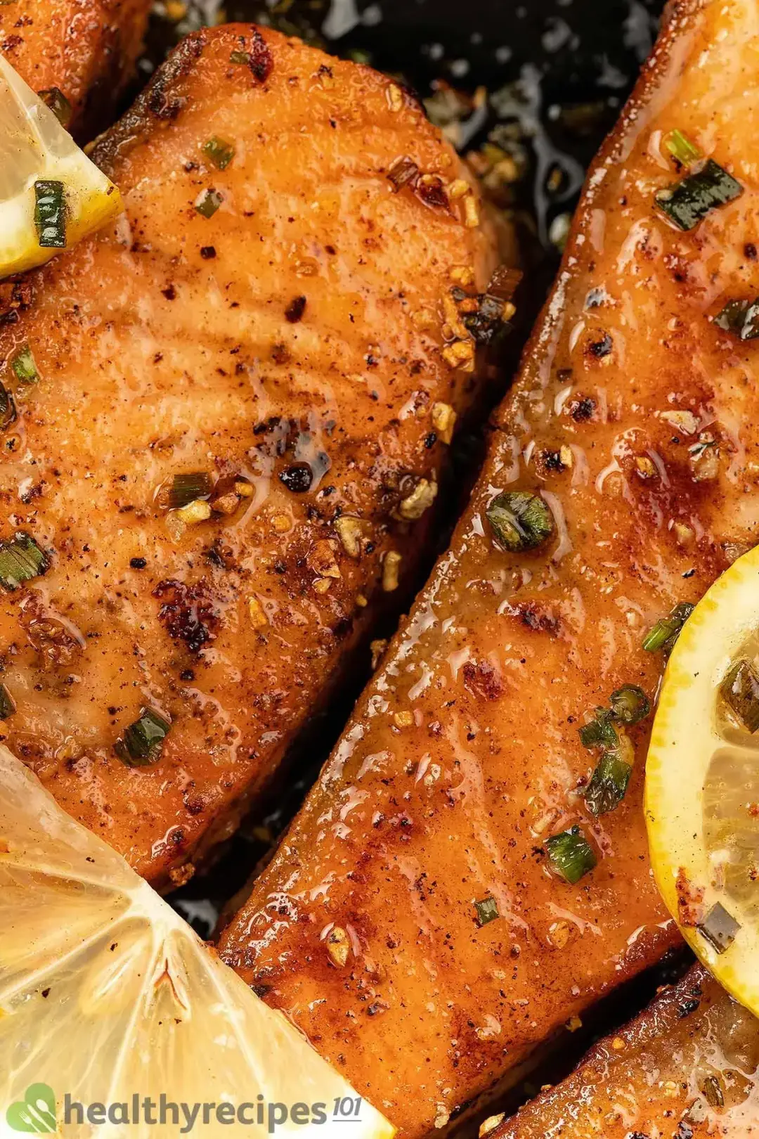 A close-up shot of charred salmon filets coated in a glossy herby sauce