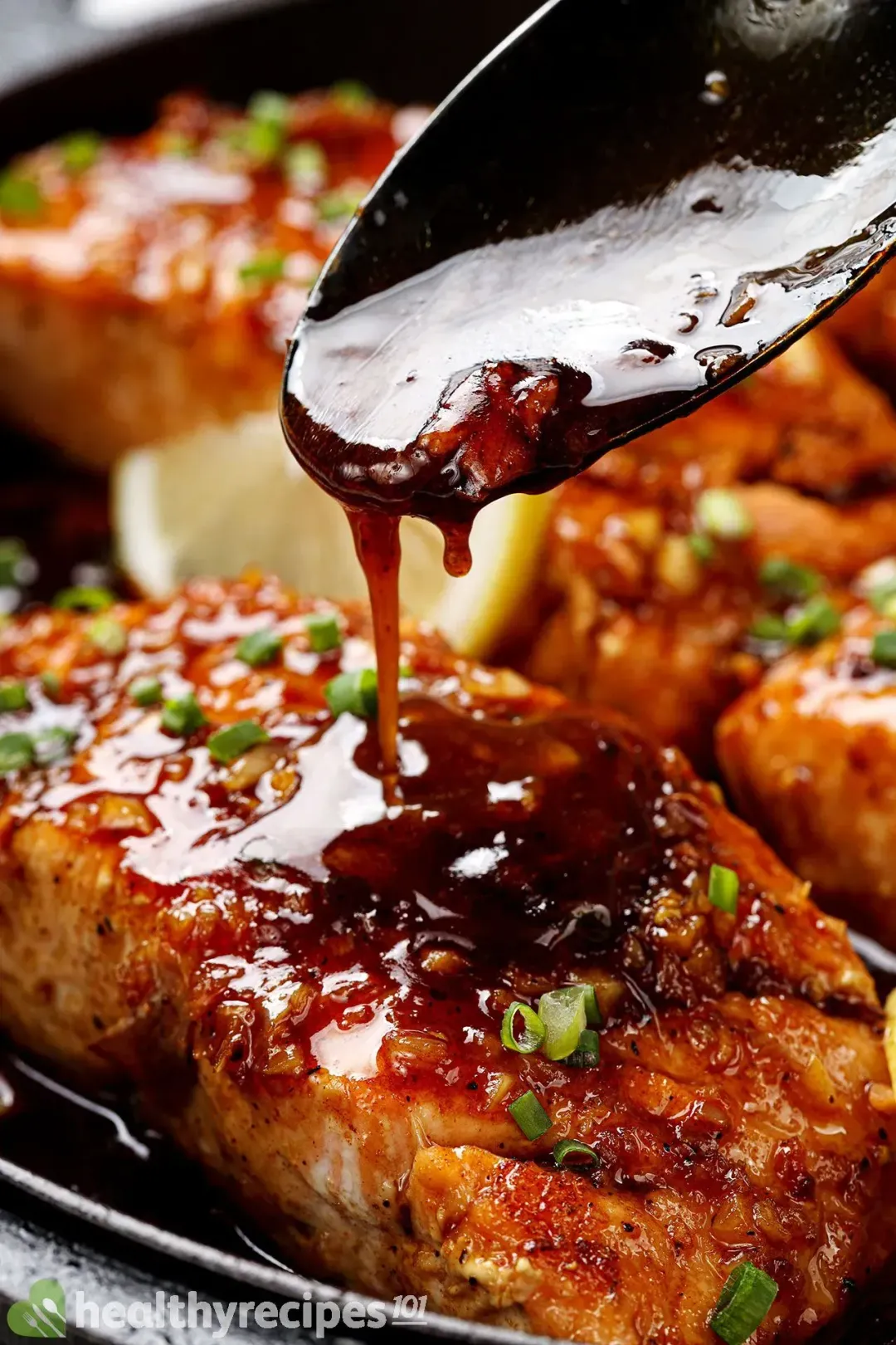  A close-up picture of a skillet of honey garlic salmon with a drizzle of honey garlic sauce