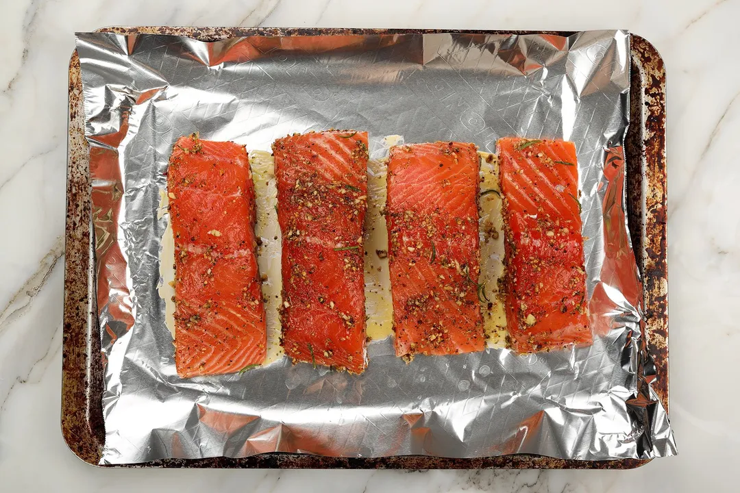 four salmon fillets bed on foil on a tray