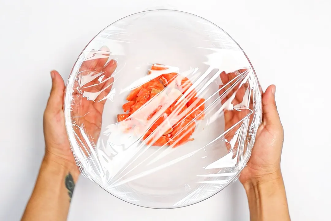 chopped salmon in a glass bowl, wrapped in plastic wrap