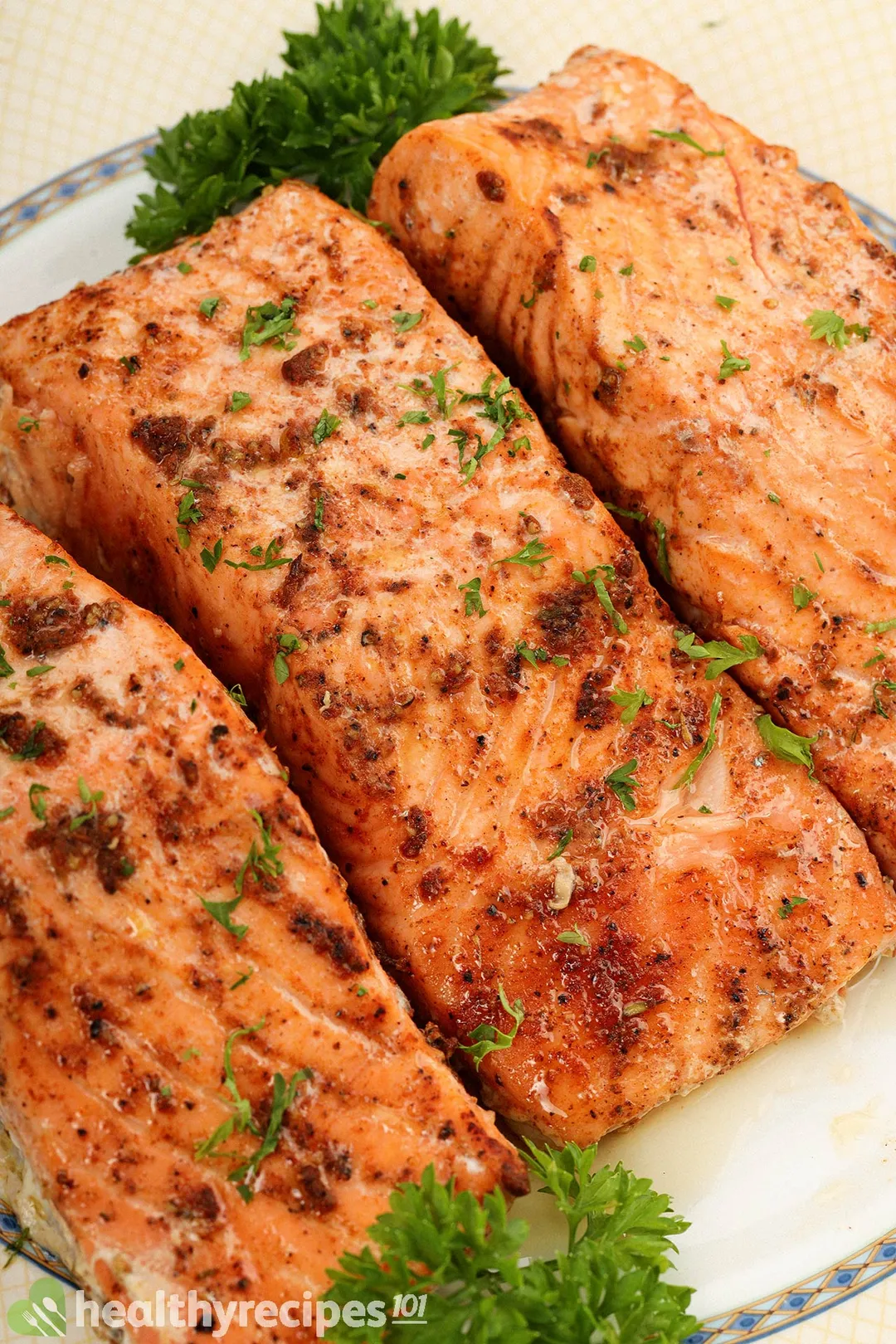 three cook salmon fillet on a plate with parsley