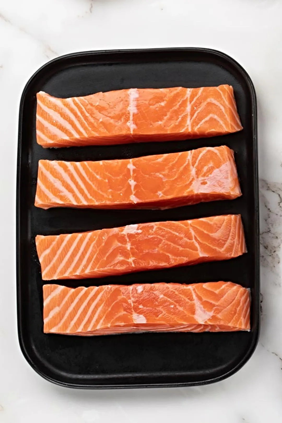 four salmon fillet on a black plate