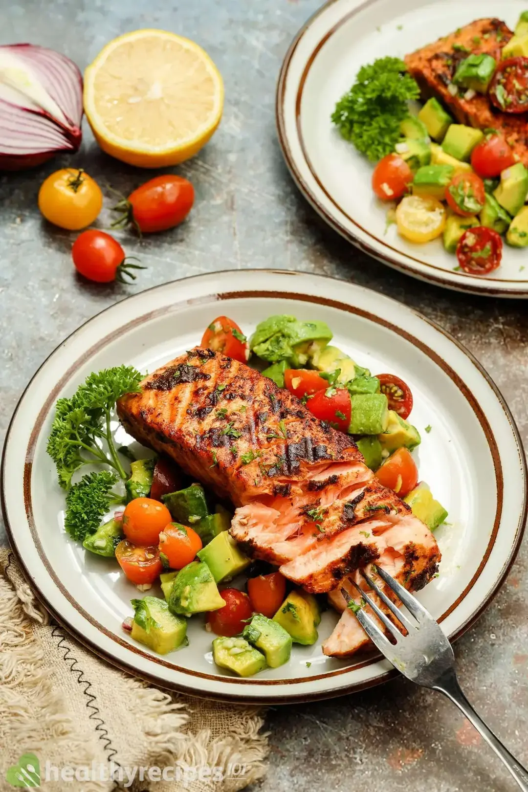 A plate of salmon avocado decorated with a fork, a tablecloth, and cherry tomatoes