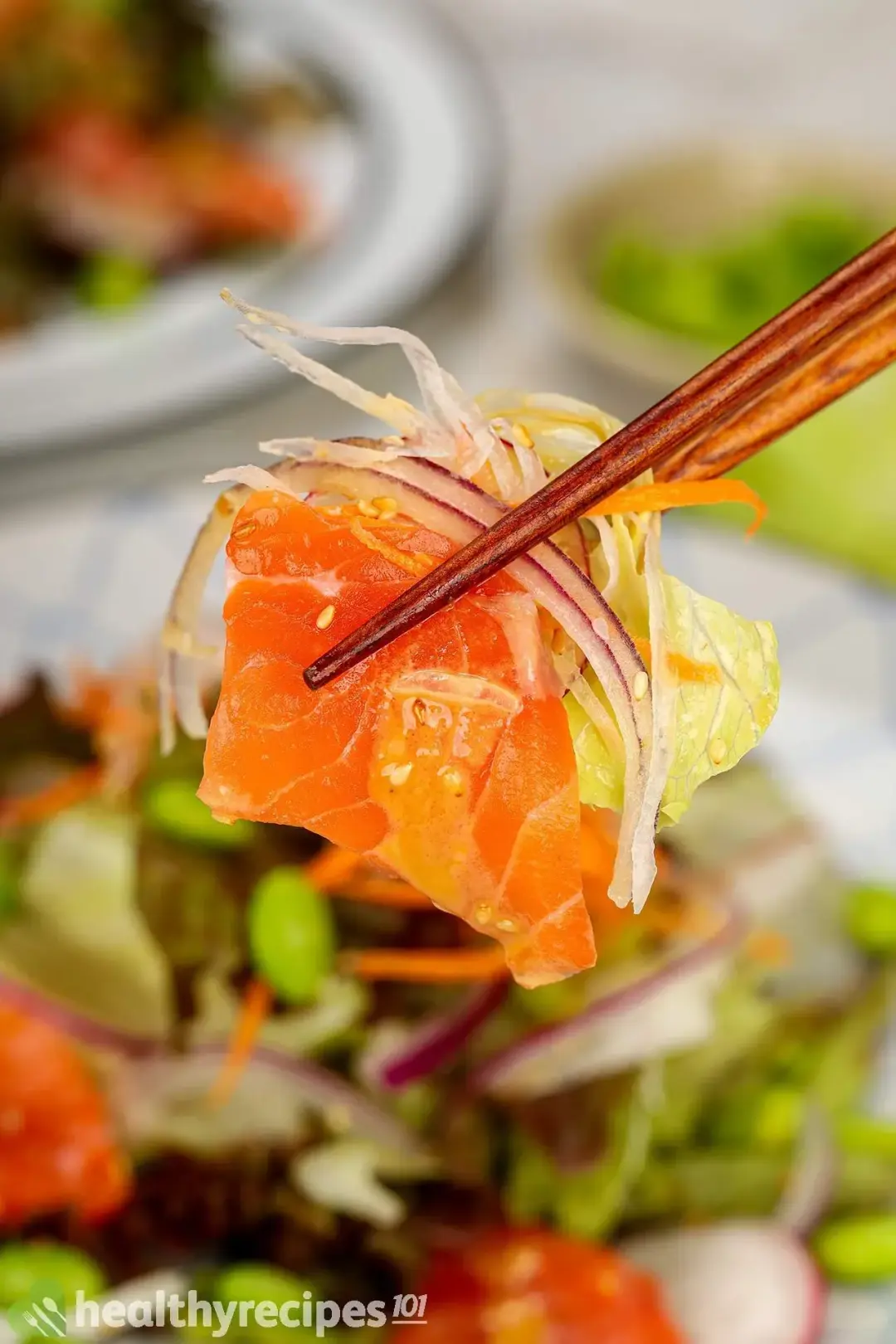 A close-up shot of a bite of Japanese salmon salad with wooden chopsticks