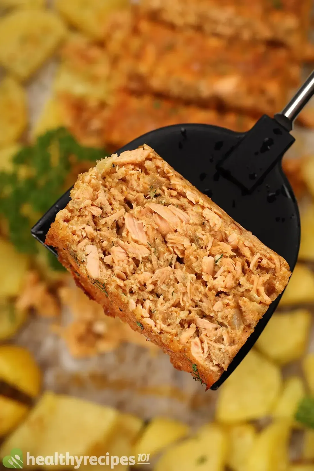 A small spatula holding up a piece of salmon cake