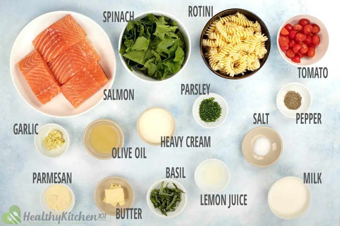 Ingredients in separate bowls and plates: salmon filets, spinach, rotini, halved cherry tomatoes, butter, spices and seaosnings