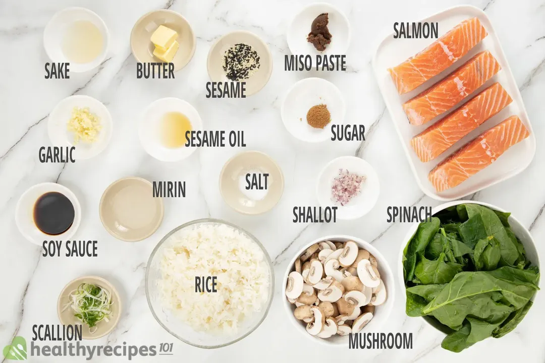 A plate containing four raw salmon fillets, a bowl of spinach leaves, a bowl of sliced cremini mushroom, and a bowl of rice laid near various condiments