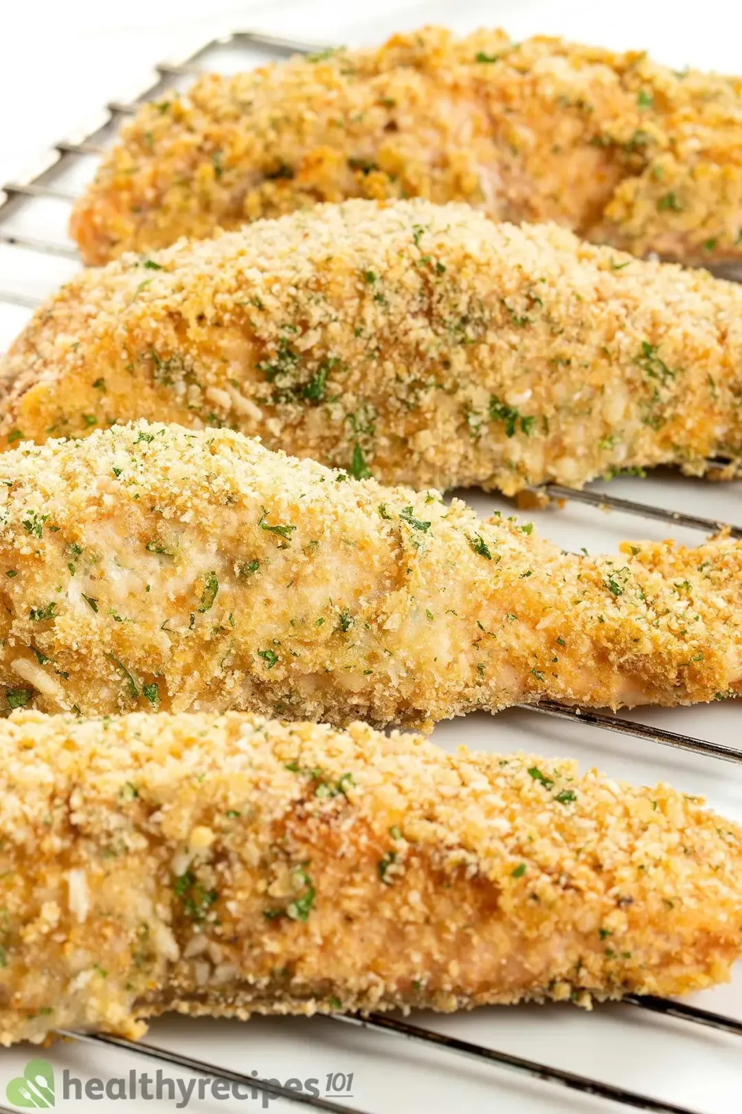Four pieces of salmon fillets crusted in parmesan and breadcrumbs laid on a cooking rack