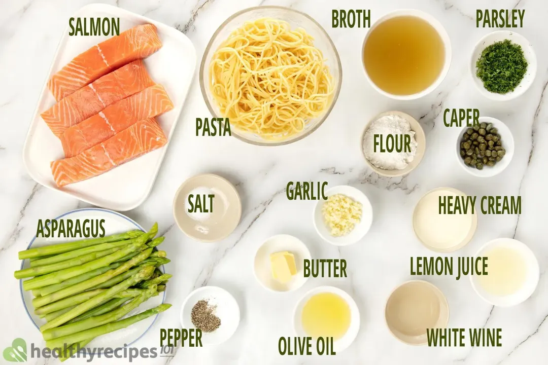 A full display of ingredients in separate bowls: salmon, asparagus, pasta, salt, pepper, broth, flour, garlic, butter, olive oil, parsley, caper, heavy cream, lemon juice, white wine.
