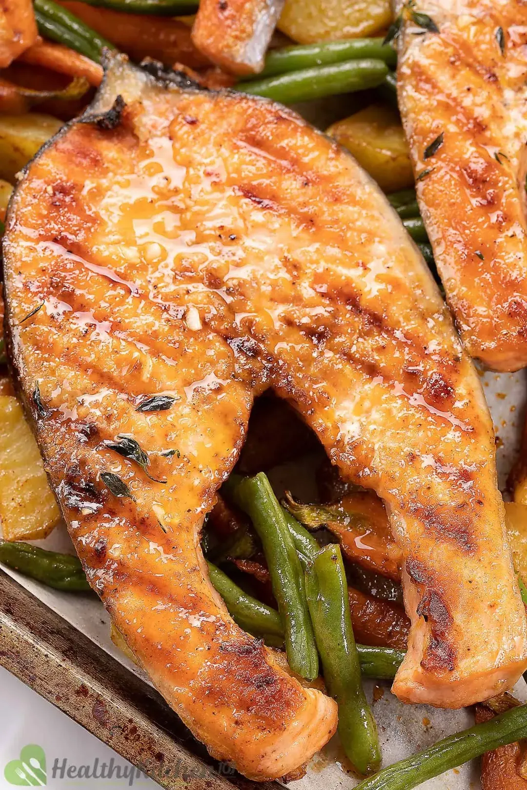 A salmon steak golden and veggies on a baking tray