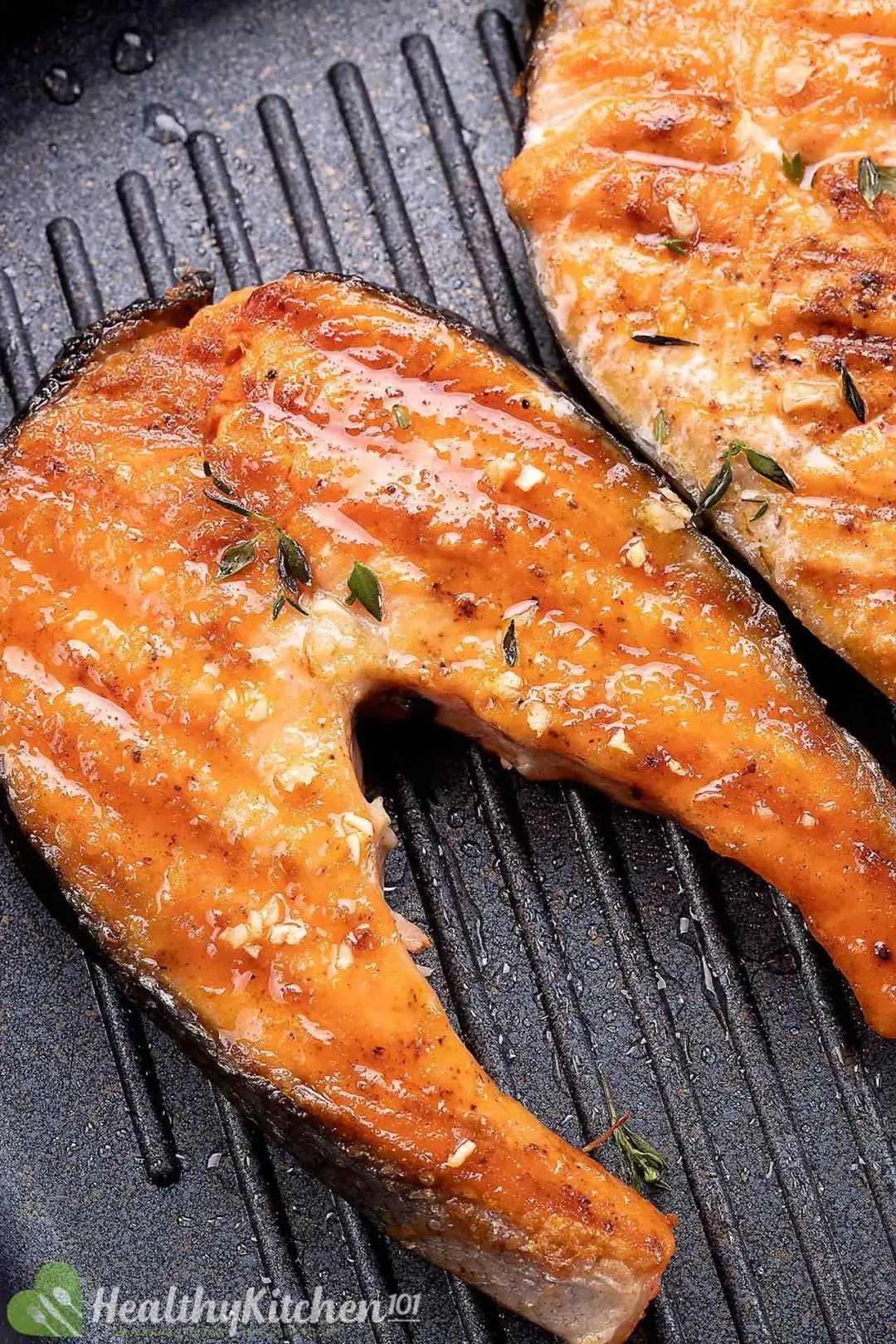Two slices of salmon steak sizzling on a grill pan