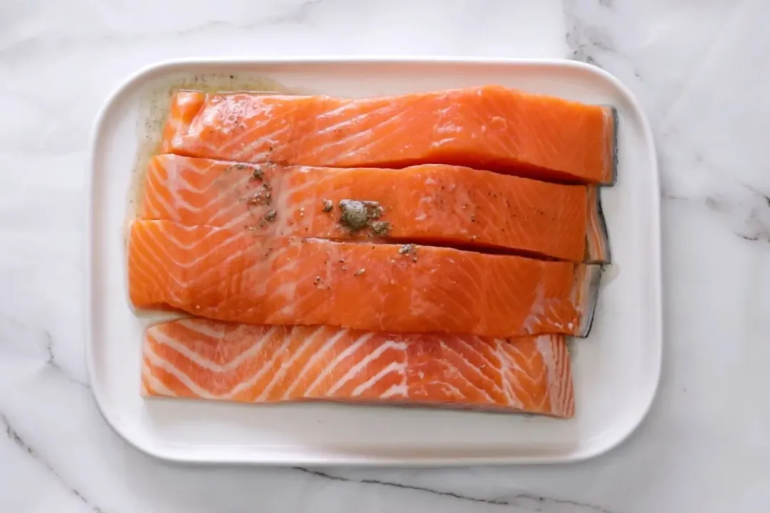 A plate of four raw salmon skin-side down.