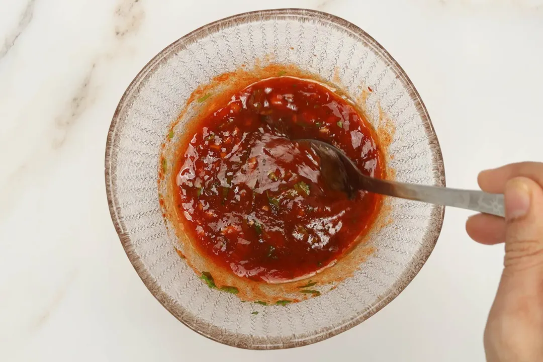 A picture of a small bowl of sauce being mixed with a spoon