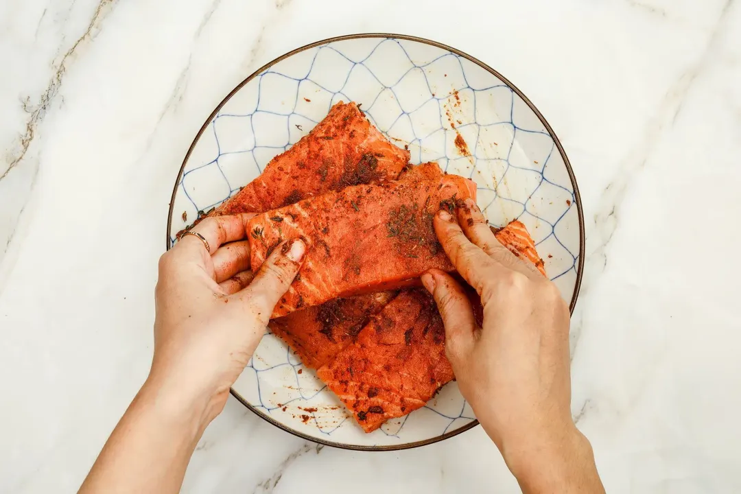 Rubbing seasoning on salmon fillets