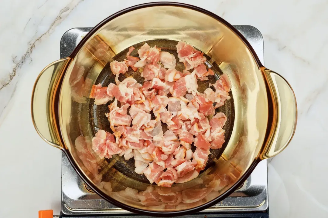 A picture of chopped bacon being seared in a large pot