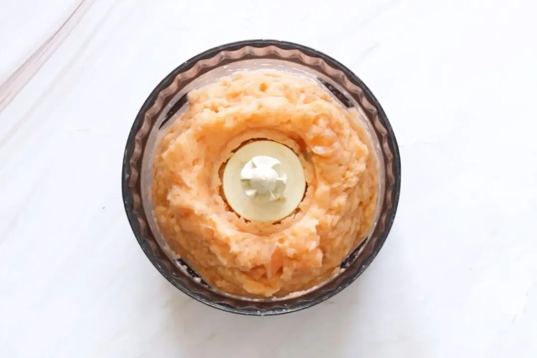 A picture of mashed salmon in a food processor taken from above.