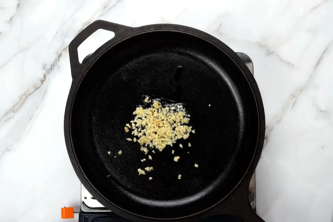 A skillet cooking finely minced garlic