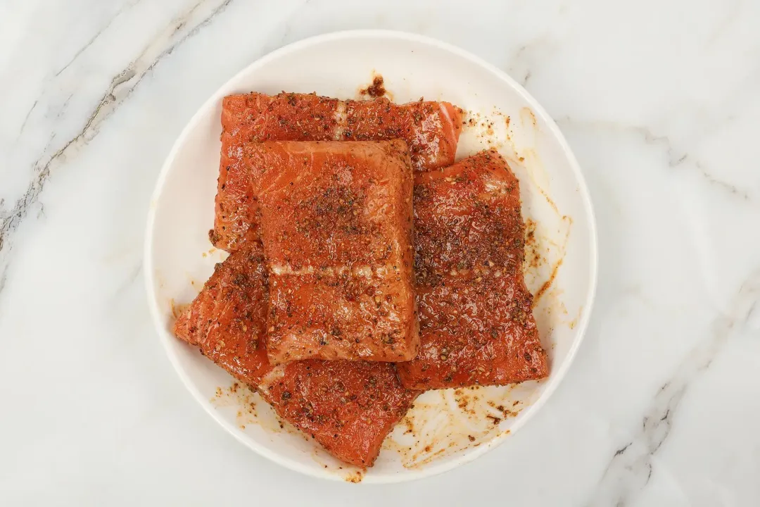 Four large uncooked salmon fillets covered in spices