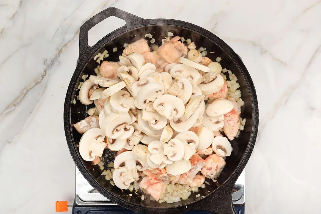 add slices mushroom to cooked salmon on a skillet