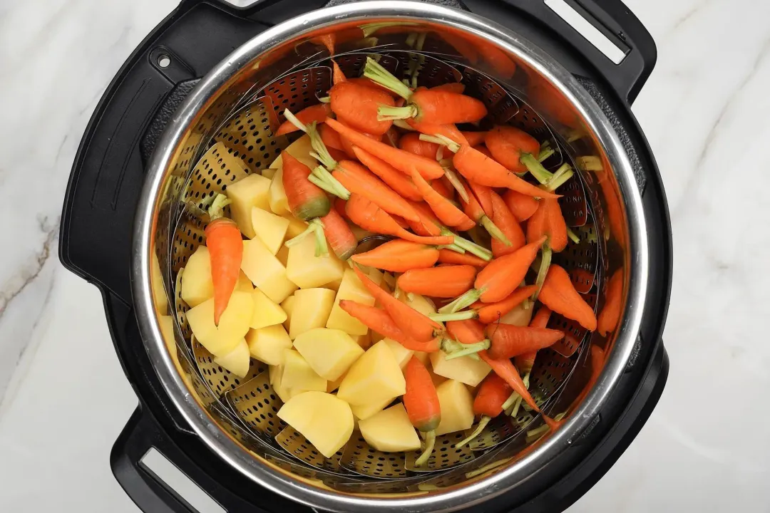 Halved baby carrots and cubed potatoes in an Instant Pot, about to be cooked