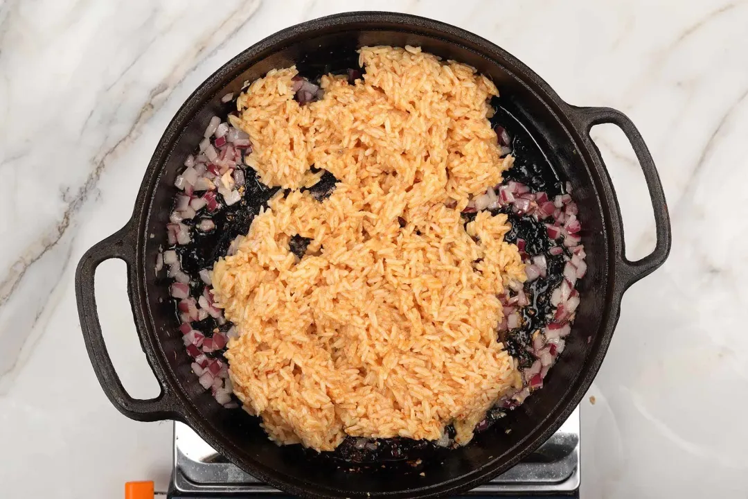 Egg-infused cooked rice added to a cast iron skillet