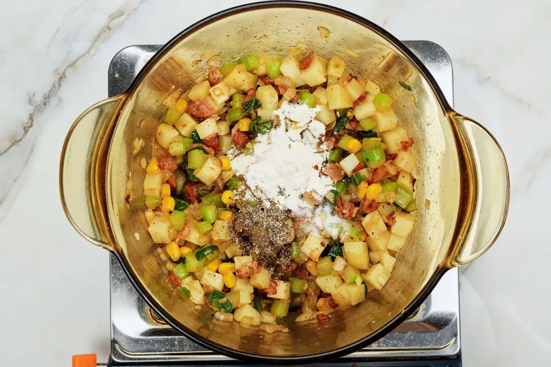 A picture of seasonings and flour being added to the pot of mixed ingredients