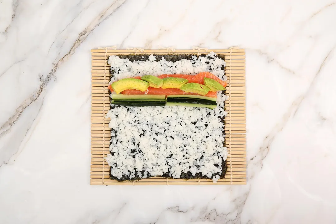 salmon slices, avocado and cucumber slices bed on rice and seaweed sheet