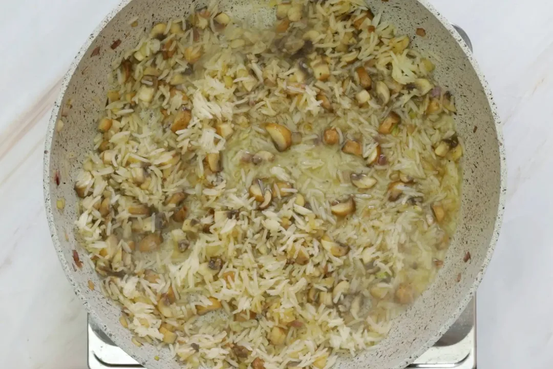 rice and mushroom cooking on a skillet