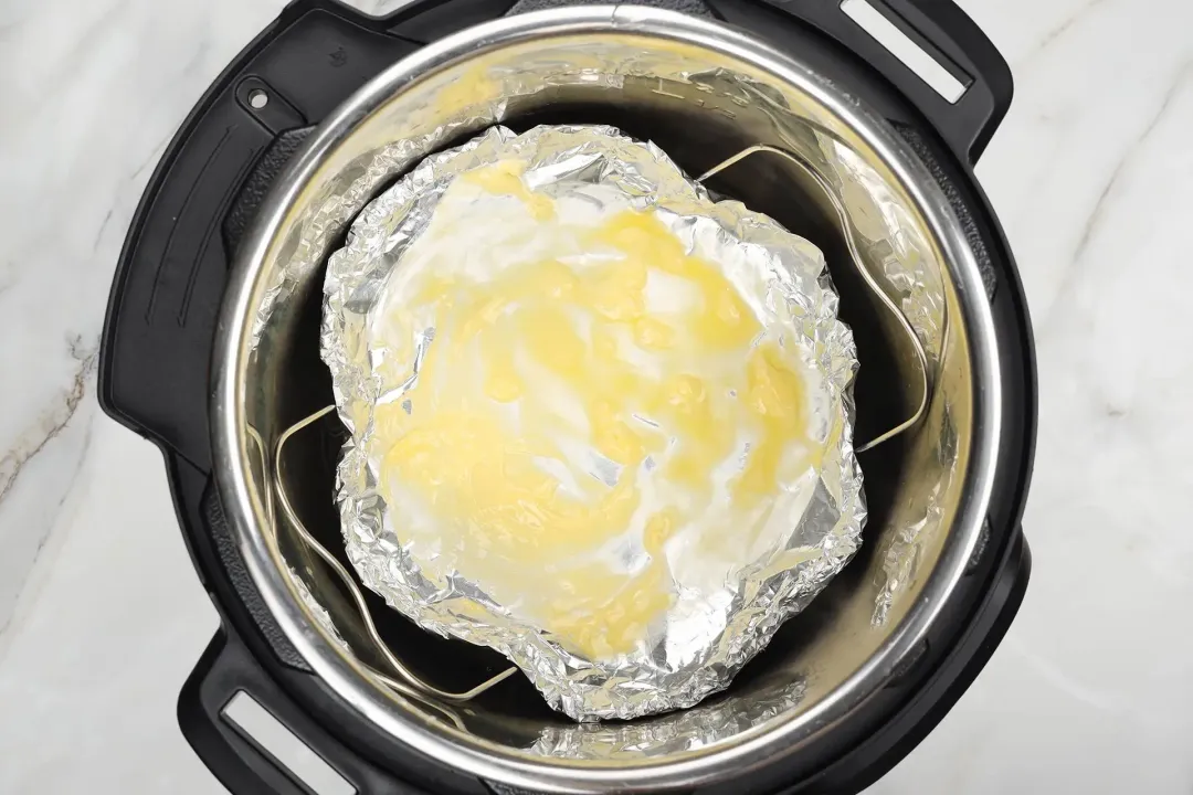 A buttered foil bowl being placed on a rack in the Intant Pot