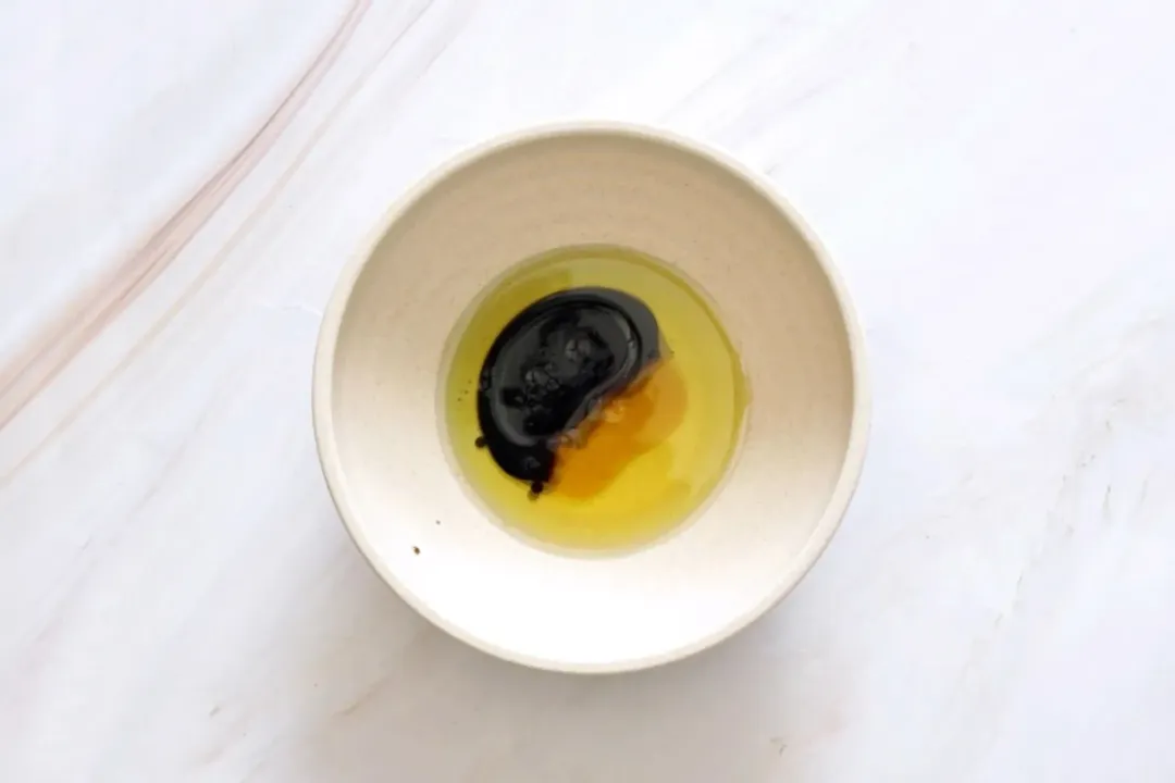 A picture of a small bowl of olive oil, balsamic vinegar, and honey in it.