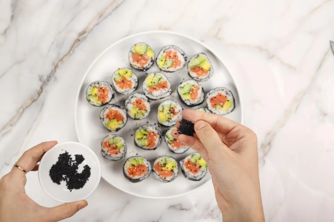 sprinkle sesame seed on sushi pieces