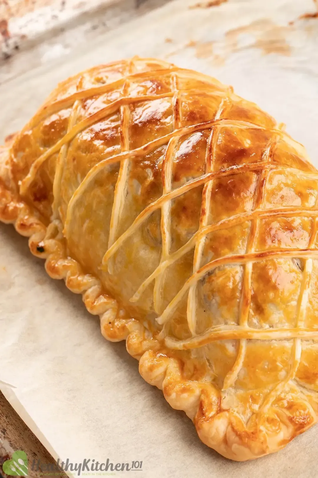 A close-up shot of a salmon en croute laid on a baking pan lined with parchment paper