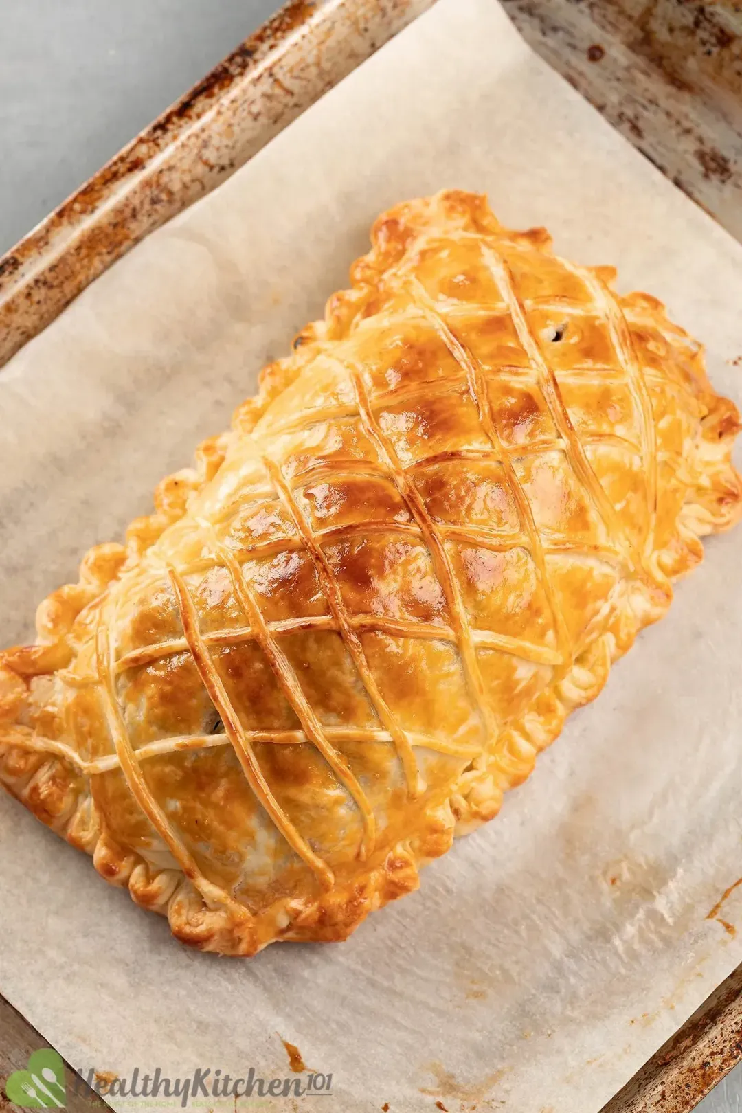 A high-angle shot of a salmon en croute laid on a baking pan lined with parchment paper